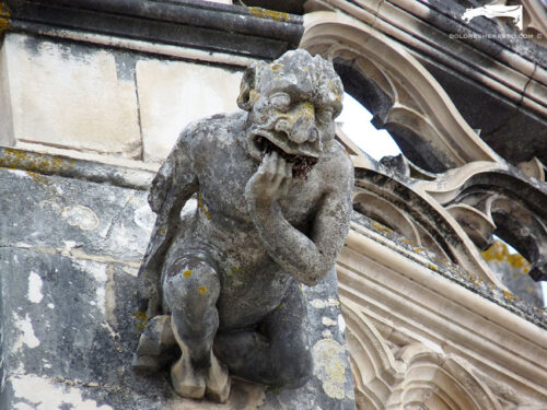 Gárgola del Monasterio de Batalha (Portugal). Es un demonio antropomorfo con una mano en la boca y dobles pezuñas.