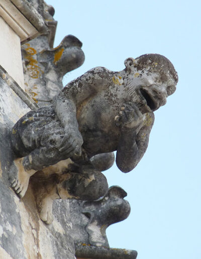Gargoyle on Batalha Monastery (Portugal). A man pulling his beard.